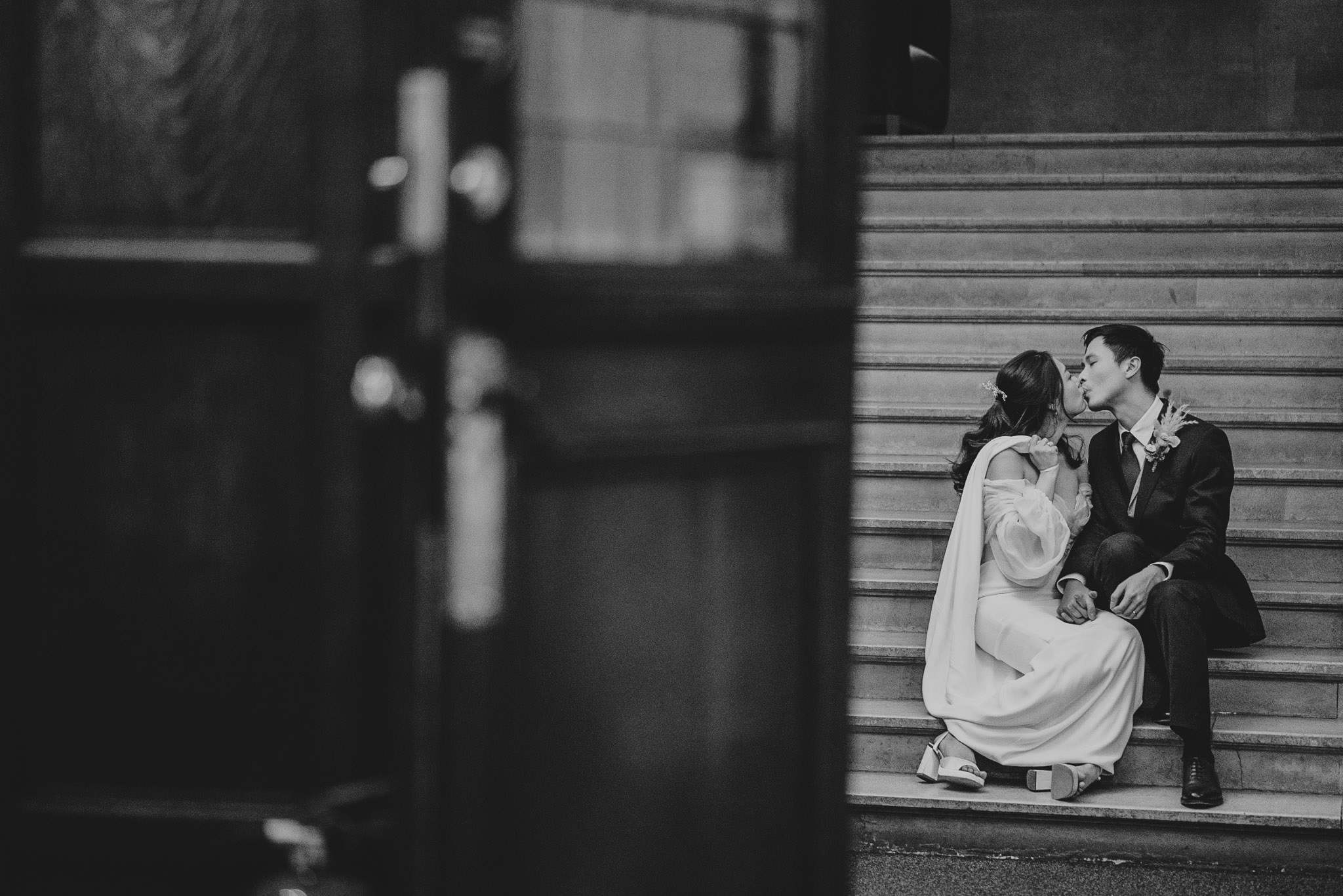 Whilst waiting to enter their Wedding Breakfast at Warminster College, the couple kiss.