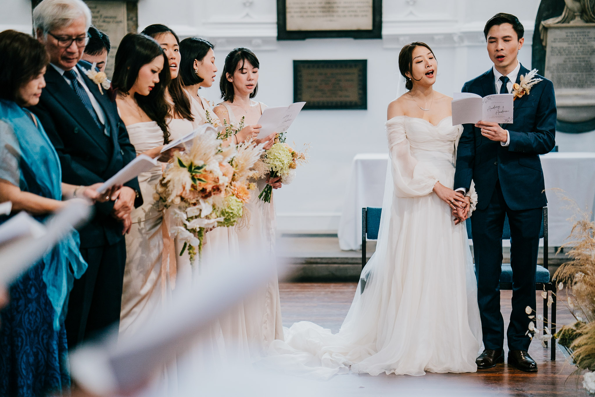 The bride, groom and guests all singing at St Andrew The Great, during their wedding.