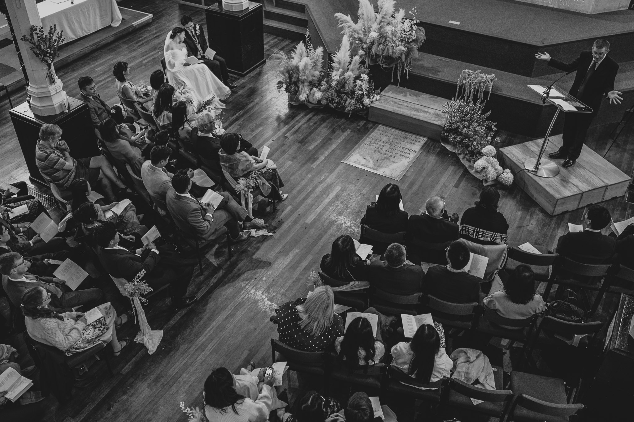 St Andrew the Great wedding ceremony, shot from above - the couple share a little moment as the pastor reads.