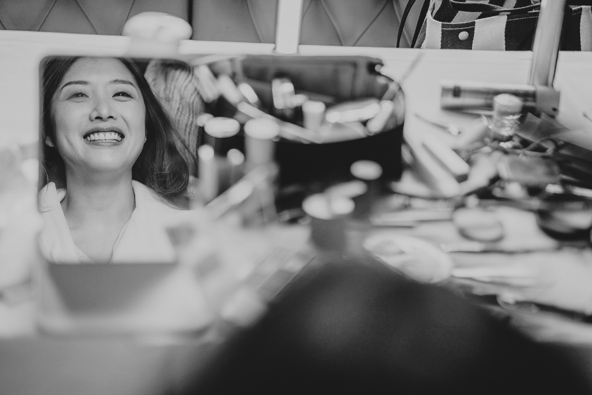 Audrey, the bride, getting ready - a reflection of her happy face in the make up artist's mirror.