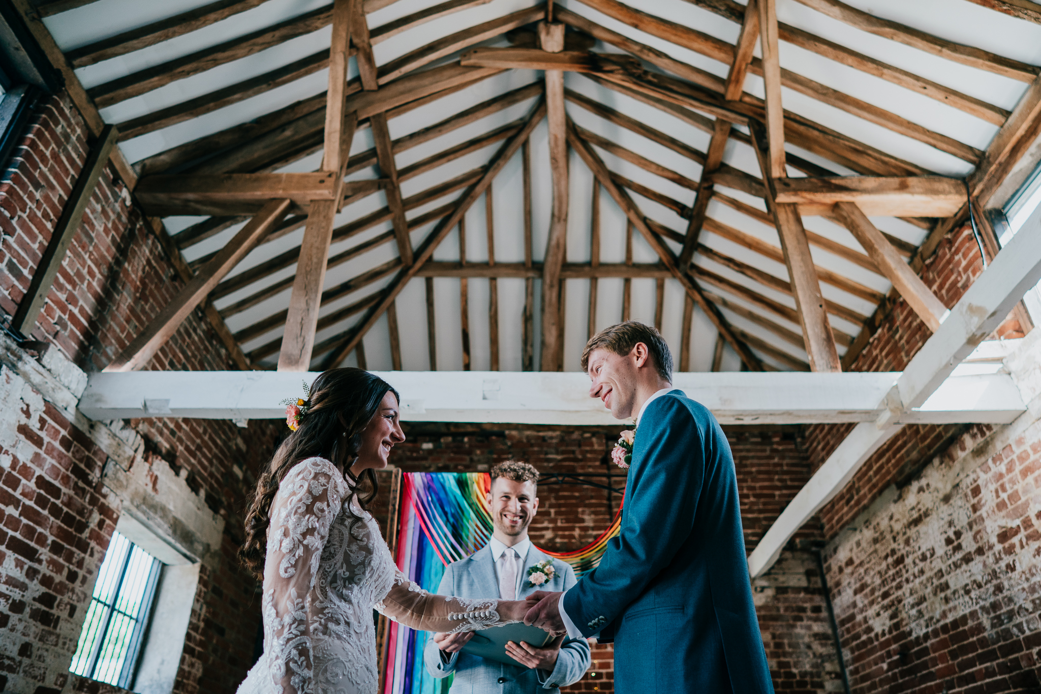 henham-park-wedding-photographer 1 – Alan Law Photography The bride and groom hold hands and smile at each other during their wedding ceremony at Henham Park, Suffolk.