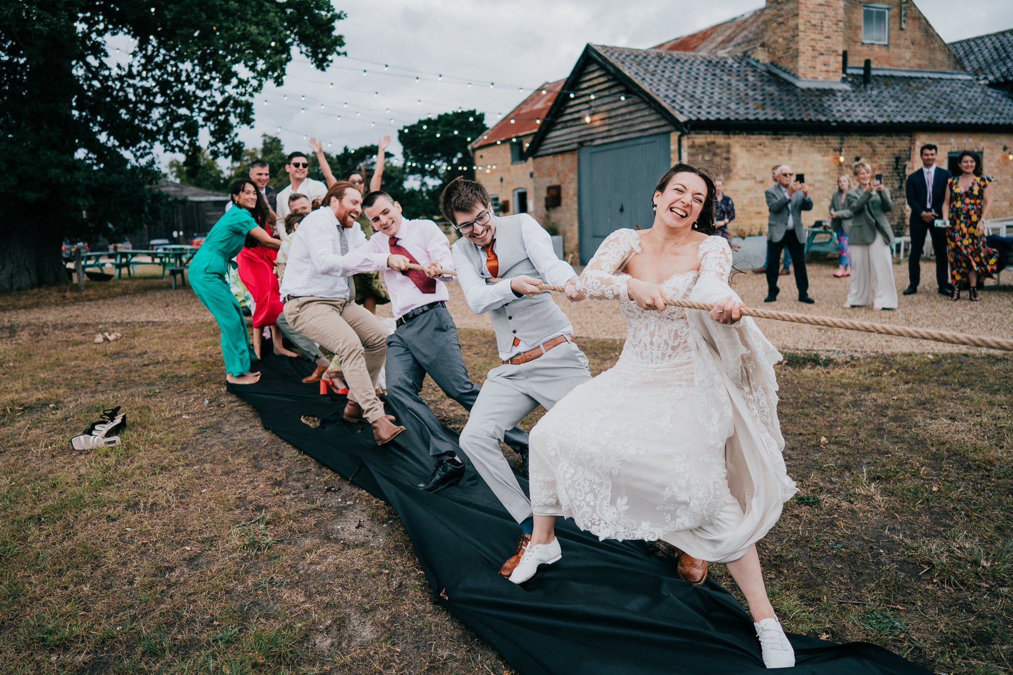 henham-park-wedding-photographer 2 – Alan Law Photography The bride and guests during tug-of-war, all laughing and having fun, at Henham Park.