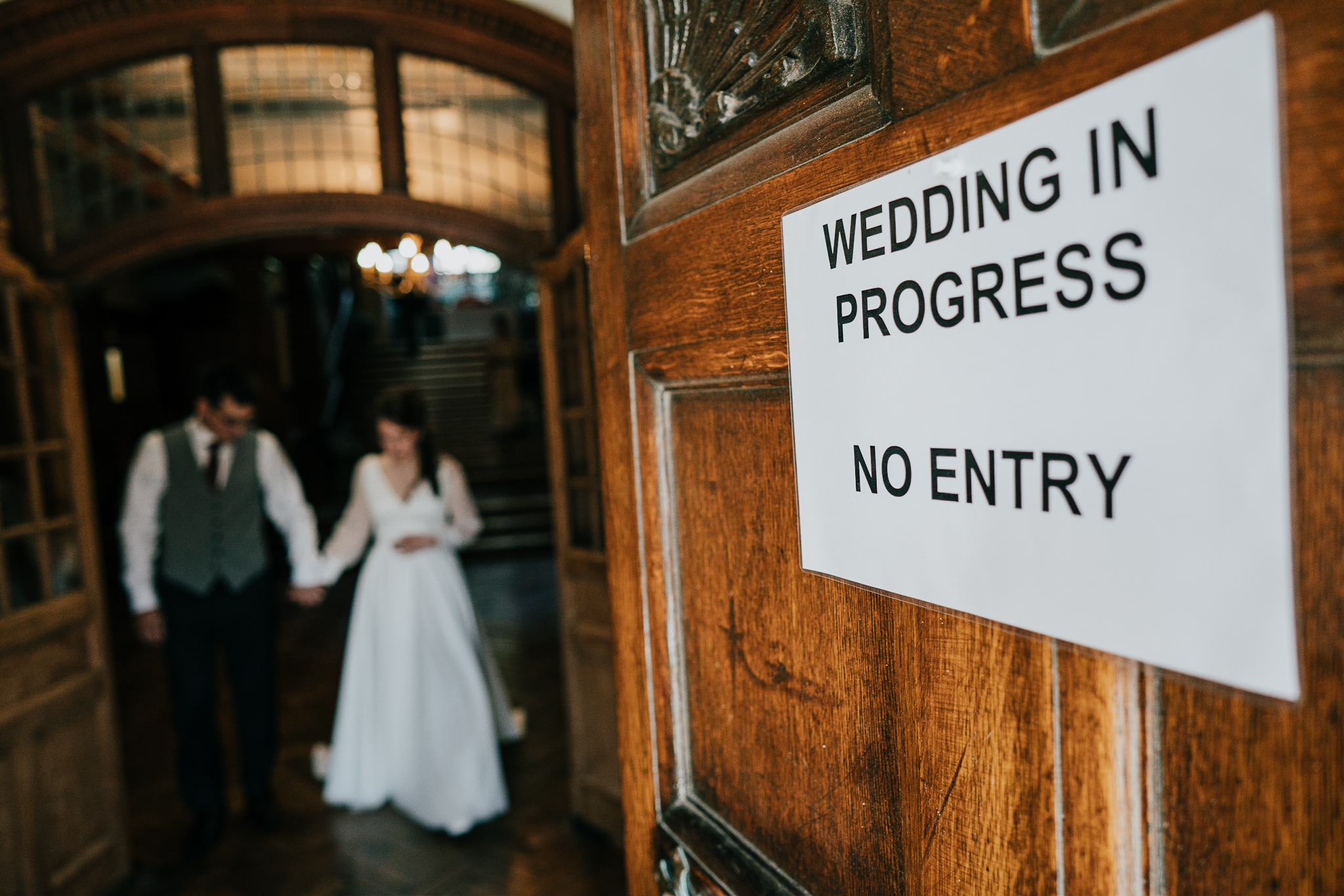 lynton-town-hall-wedding-photographer 1 – Alan Law Photography A sign reads'Wedding in progress - no entry' as the bride and groom, out of focus, are walking in the background.