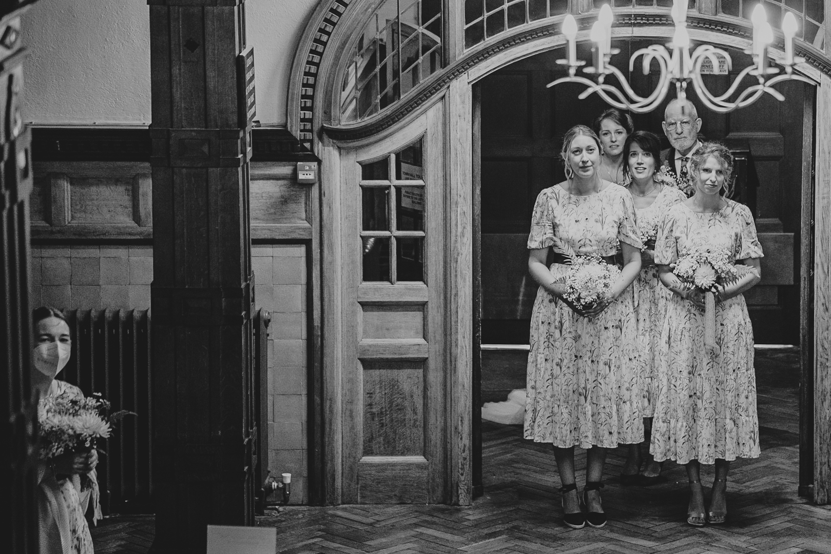 lynton-town-hall-wedding-photographer 9 – Alan Law Photography Just before their Lynton Town Hall wedding ceremony, Penny and her bridesmaids wait to enter the room - including one who is wearing a face-mask, keeping herself distant from the rest.