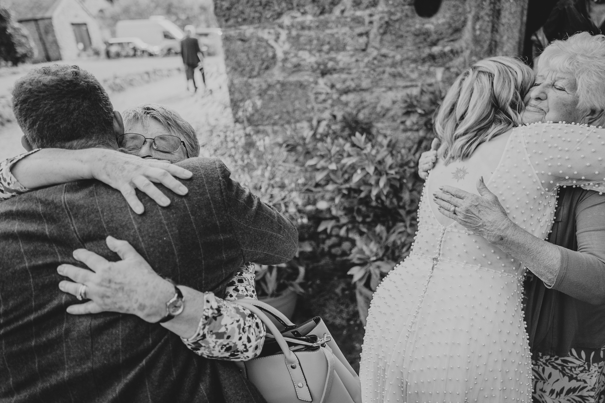 pengersick-castle-wedding-photographer 5 – Alan Law Photography Two separate hugs at Pengersick Castle - the bride and groom being congratulated by guests.