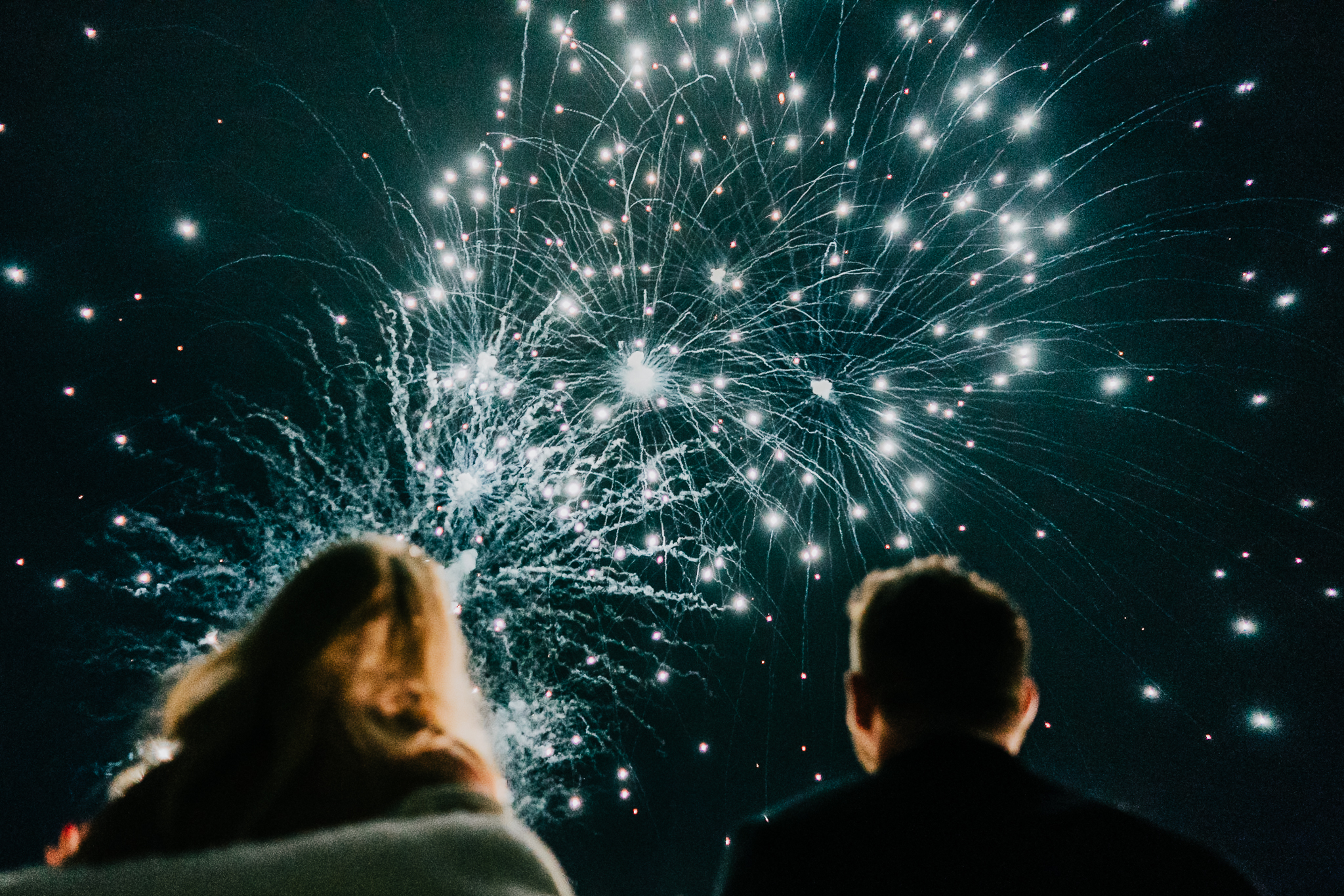 Fireworks light up the sky at Polhawn Fort, with the bride and groom watching from below.
