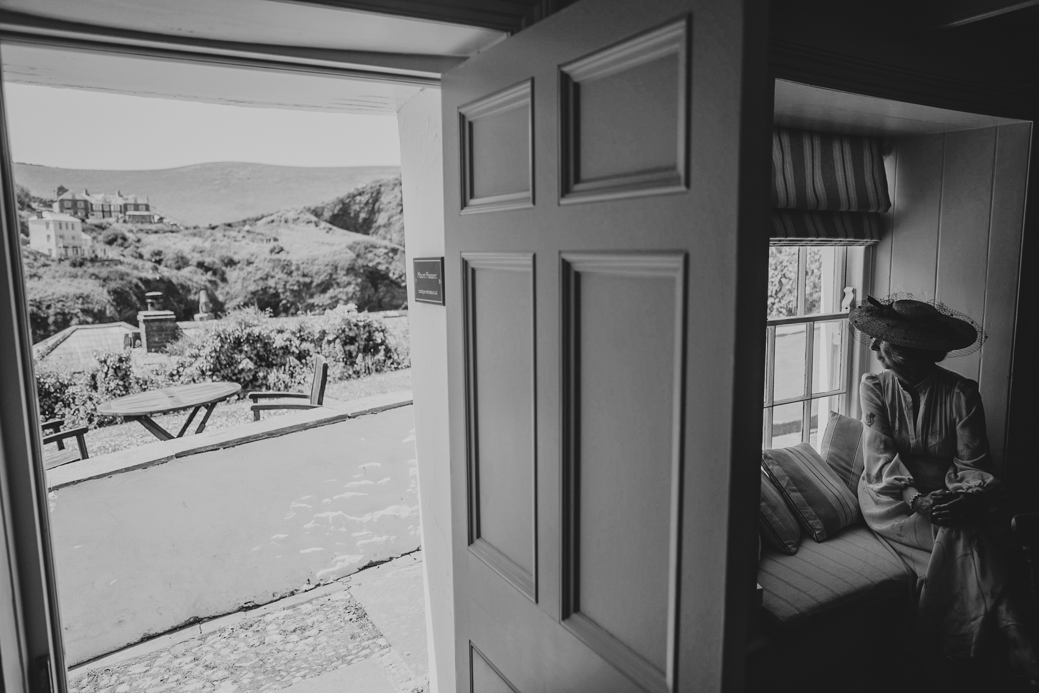 port-isaac-wedding-photographer 4 – Alan Law Photography The mother of the bride looks back through a window at the village of Port Isaac, Cornwall.
