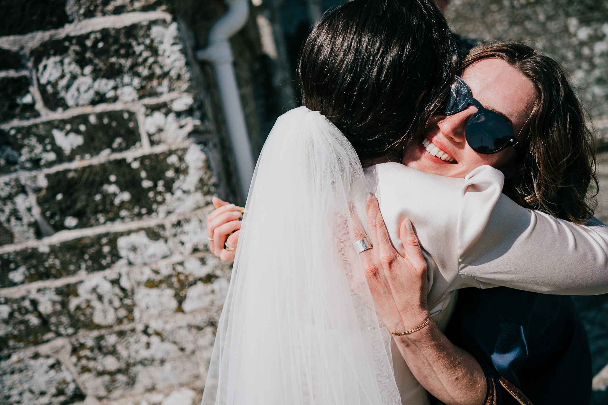 port-isaac-wedding-photographer 5 – Alan Law Photography A guest hugs the bride outside St Endellion Church.
