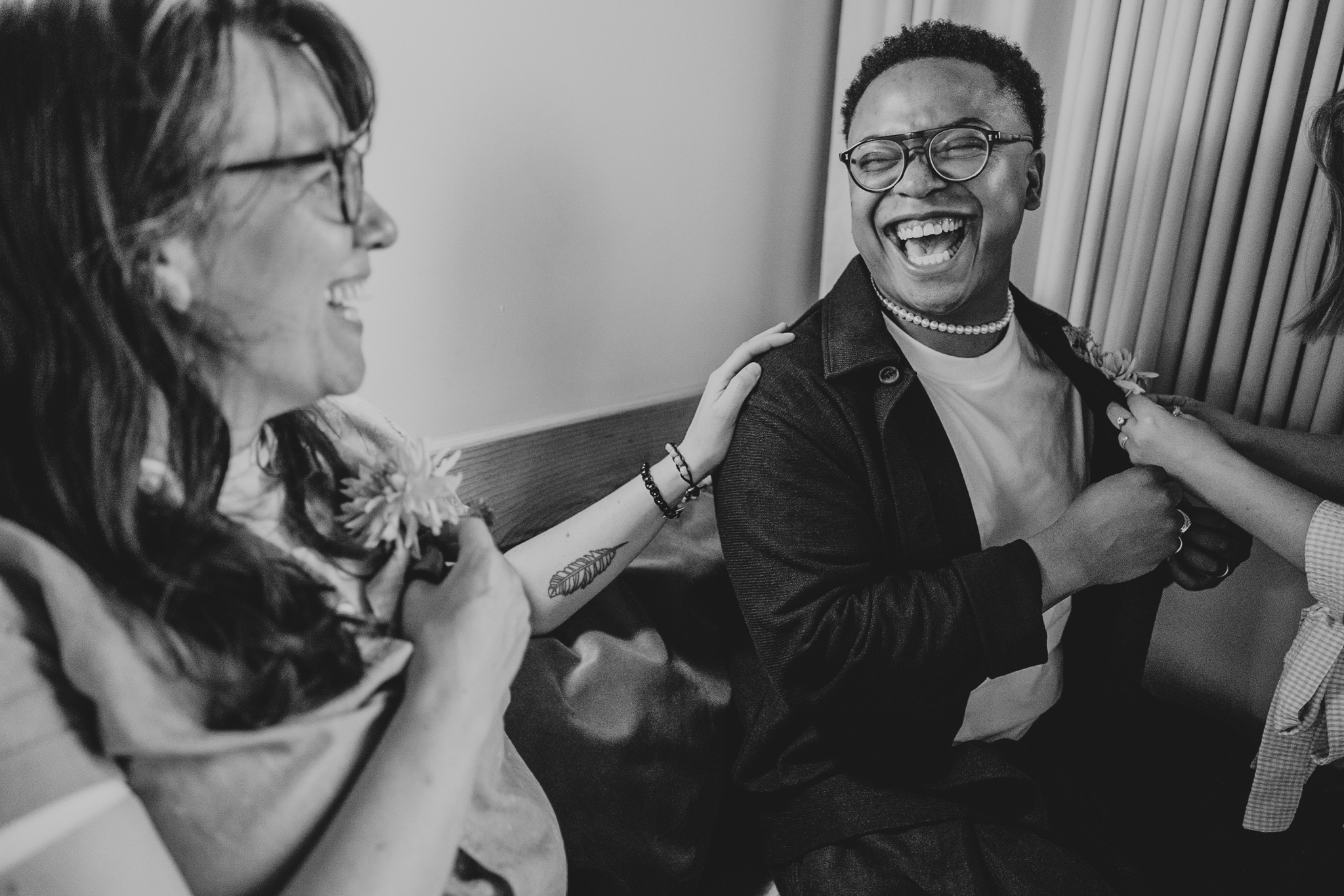 The Best Man laughs with the Best Woman as their button-holes go on.