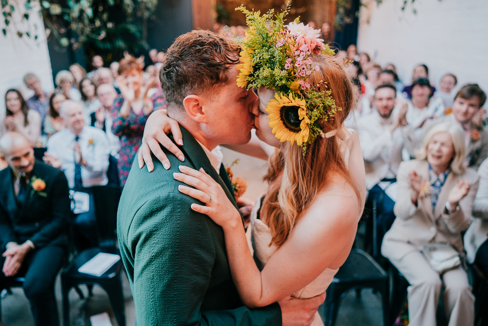 Brdie and groom share their First Kiss at The Hackney, with the bride wearing a huge sunflower head dress.